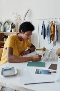 Writer attempting NaNoWriMo possibly Boy Wearing Yellow Shirt While Writing on White Paper