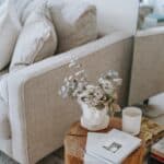 Creative Mashups ~ Cozy sofa with decorative cushions near stump with books and blooming flowers in vase in house room