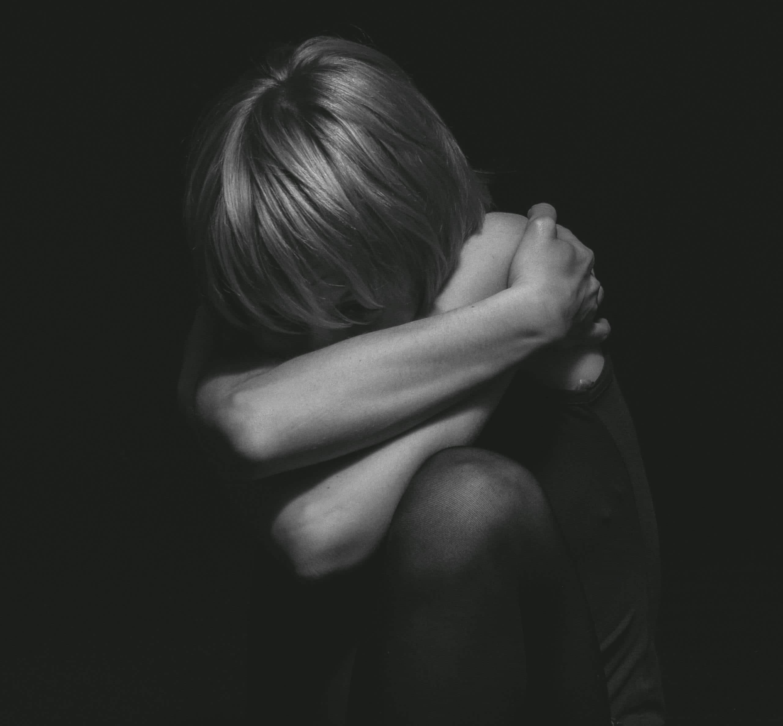 Cutting Words ~ Grayscale Photo of a Person Hugging Self